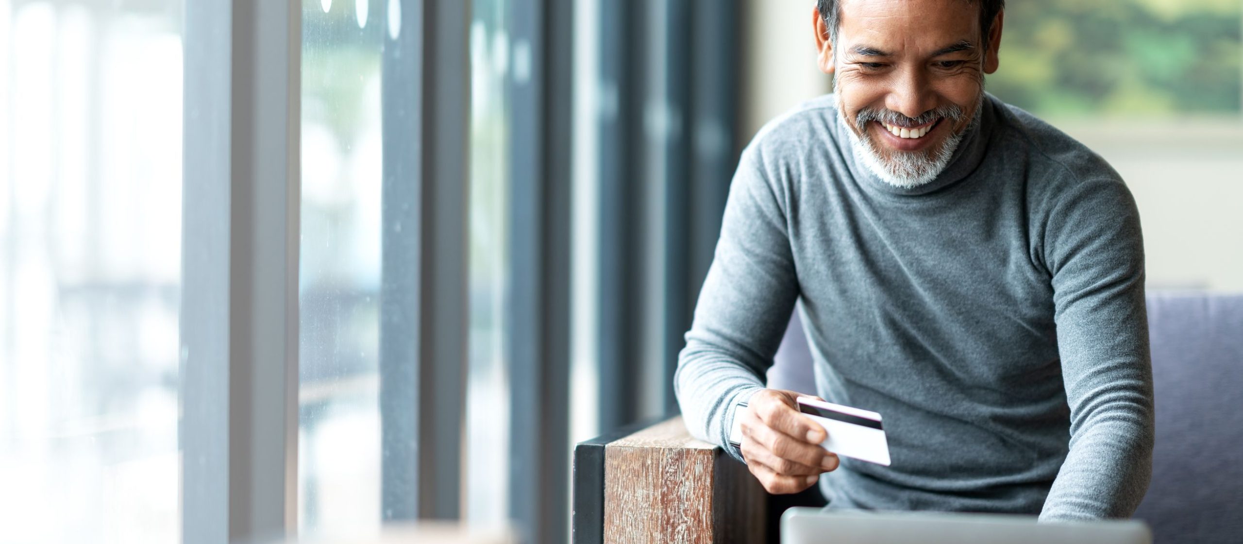 Attractive bearded hipster asian father or Hispanic old man using Laptop and credit card.